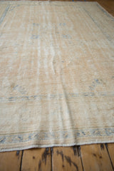 Distressed Oushak rug pile texture with worn cream tones and faded blue details.