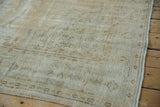 Close-up of vintage distressed Oushak carpet, showing worn pile, exposed foundation, and intact side selvage.