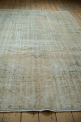 Textural close-up of distressed vintage Oushak carpet, with visible knot heads in muted cream, brown.