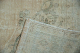 Distressed Oushak pile in cream with visible foundation and hand-knotted reverse.