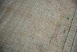 Distressed texture of a Vintage Oushak rug showing worn pile, beige tones, and faint green motifs.