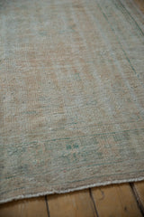 Distressed Oushak carpet, showing worn foundation, pale apricot, seafoam green, and red speckling.