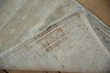 Distressed vintage Oushak rug corner showing beige pile, side selvage, and woven foundation.