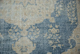 Distressed Sparta carpet detail with worn pile revealing foundation, in dusty blue and cream motifs.