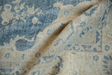 Folded texture of a vintage distressed Sparta carpet with worn denim blue and ivory patterns.