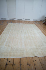 Distressed Oushak carpet's end, highlighting pale beige and cream tones with visible foundation wear.