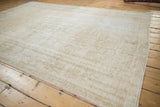 Distressed Oushak rug texture showing wear across knot heads with cream and pale sage.