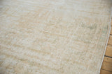 Distressed vintage Oushak rug pile showing wear with cream, ivory, and sage green hues.