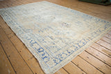 Distressed vintage Oushak rug corner, showing worn floral border in cream and blue.