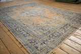 Distressed Oushak carpet with worn apricot orange field, cobalt blue motifs, and intact selvage.