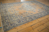 Distressed apricot orange Oushak rug with time-softened cobalt blue motifs and visible side selvage.