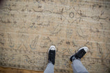 Worn texture of distressed Oushak rug, showing faded beige, brown, and blue floral motifs.
