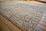 Distressed vintage Oushak carpet corner, showing worn beige, brown, and blue botehs.