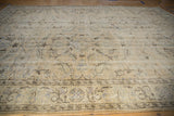 Distressed Oushak carpet detail: faded beige field with blue paisley motifs and low pile.