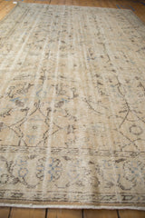 Distressed Oushak carpet detail: worn antique ivory pile, visible foundation, brown paisley, blue motifs.
