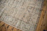 Distressed Oushak rug's main border with faded floral and vine motifs in beige, blue, and brown.