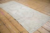 Distressed Oushak runner with dusty rose serrated spandrel and pale bronze geometric plant motif.
