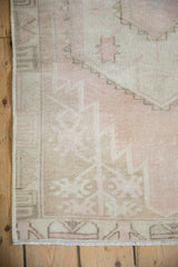 Vintage distressed Oushak rug corner with secured binding, showing worn dusty rose and bronze pile.