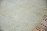 Textured distressed Oushak carpet, showing worn pile, visible foundation, and subtle blue patterns.