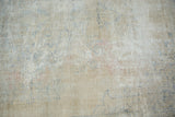 Distressed Oushak rug's worn texture, revealing beige pile, exposed foundation, and dusty blue.