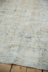Textural close-up: Distressed vintage Oushak pile in beige, dusty blue, foundation showing.