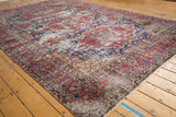 Distressed vintage Oushak carpet showing black cherry red, midnight blue floral design, and corner stain.