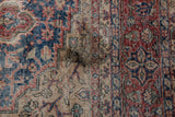 Distressed vintage Oushak carpet with dark stain and worn pile.