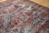 Distressed Vintage Oushak carpet close-up: black cherry red, midnight blue floral patterns with exposed foundation.