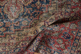 Distressed vintage Oushak carpet's worn black cherry red, midnight blue, and beige floral designs.