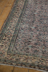 Vintage distressed Oushak rug showing muted aubergine field and patterned ivory border with wear.