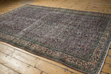 Distressed Oushak rug corner, worn pile, scrolling vine border in aubergine, green, ivory.