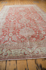 Distressed Sivas carpet border with geometric vines, serpent motifs, and worn brick red field.
