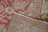 Corner of distressed Sivas carpet, revealing worn brick red floral pile and the reverse foundation.