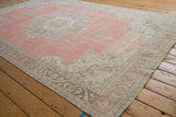 Distressed rose-pink field and ornate vine-and-leaf border of a vintage Turkish Sparta carpet.