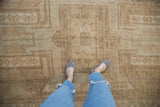 Distressed vintage Oushak rug displaying beige and coffee brown geometric border patterns with aged texture.
