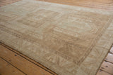 Vintage Distressed Oushak rug corner displaying worn texture, beige tones, and a geometric serrated leaf border.