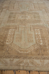 Distressed Oushak rug section with faded shield medallion and geometric motifs in neutral tones.