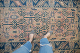 Distressed vintage Melas rug: dusty rose field, indigo geometric motifs, wide main border.