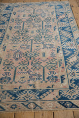 Distressed vintage Melas rug detail, indigo geometric vinery over dusty rose field.