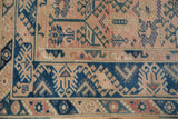 Distressed Melas rug corner, showing indigo vinery on dusty rose and geometric border.