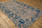 Distressed Melas rug corner with wide indigo border, geometric vinery, and intact selvage.
