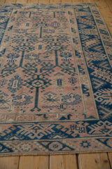 Distressed Melas rug's indigo geometric vinery, dusty rose field, and reciprocating contour border.