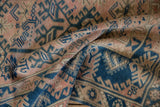 Folded vintage Turkish Melas rug, showing distressed dusty rose and indigo geometric vinery.