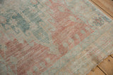 Faded floral motifs on the distressed Oushak rug pile with rose, ocean green, and ivory.