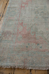 Distressed vintage Oushak rug, faded rose and ocean green floral motifs, with fringe.