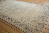 Distressed vintage Oushak carpet, with faded vinery and meandering border in neutral beige, charcoal.