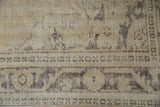 Distressed vintage Oushak carpet detail, showing faint foundation and muted charcoal border.
