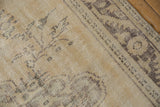 Distressed vintage Oushak carpet showing faded charcoal vinery, beige pile, and visible foundation.
