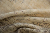 Folded texture of vintage distressed Oushak rug with muted beige and charcoal floral vinery.