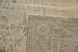 Distressed vintage Oushak rug's beige pile showing even wear to knot heads and fringed foundation.